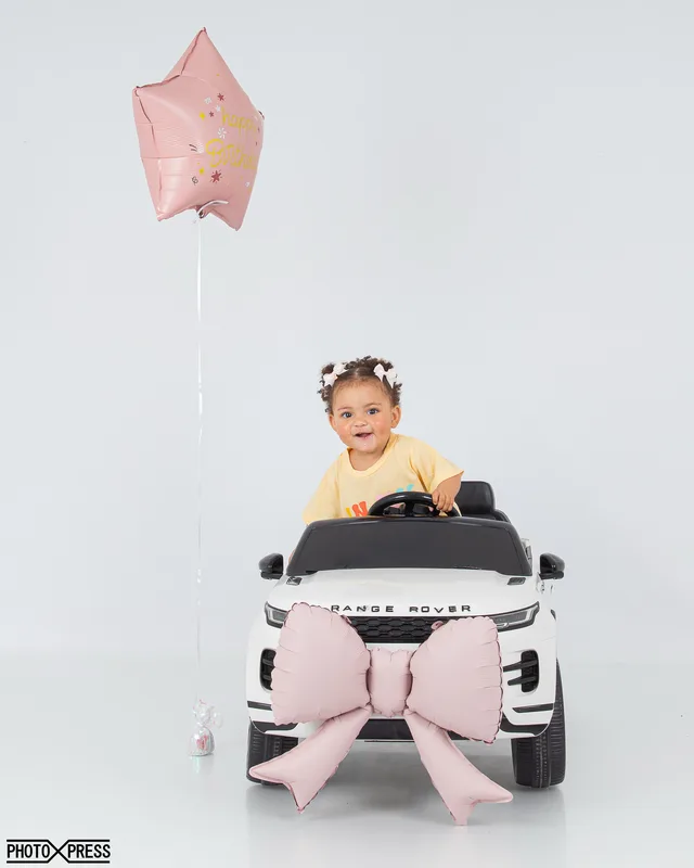 First birthday photoshoot, girl in a toy car