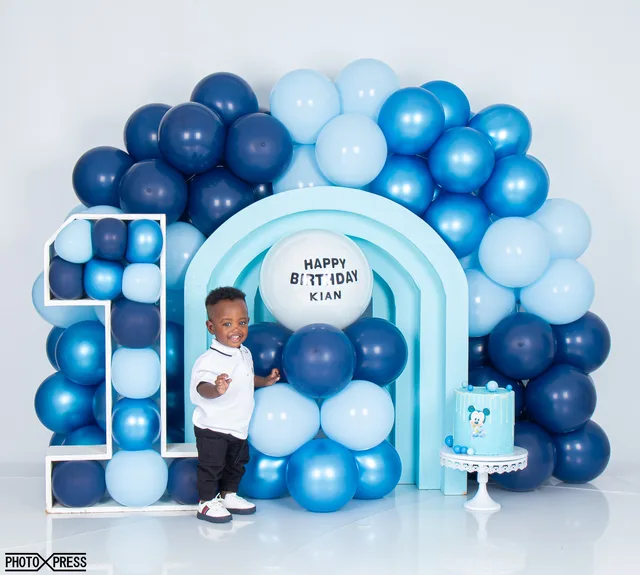 First birthday photoshoot, boy standing with a blue balloon arch