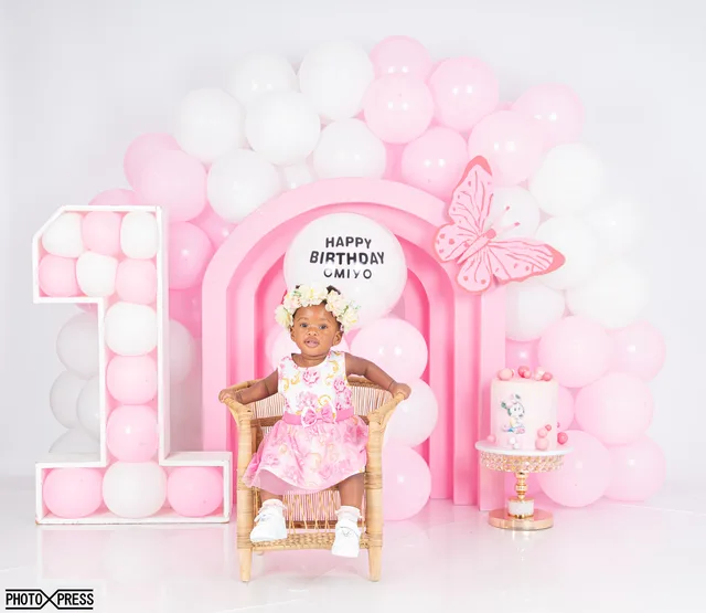 First birthday photoshoot, girl in a chair with a pink balloon arch